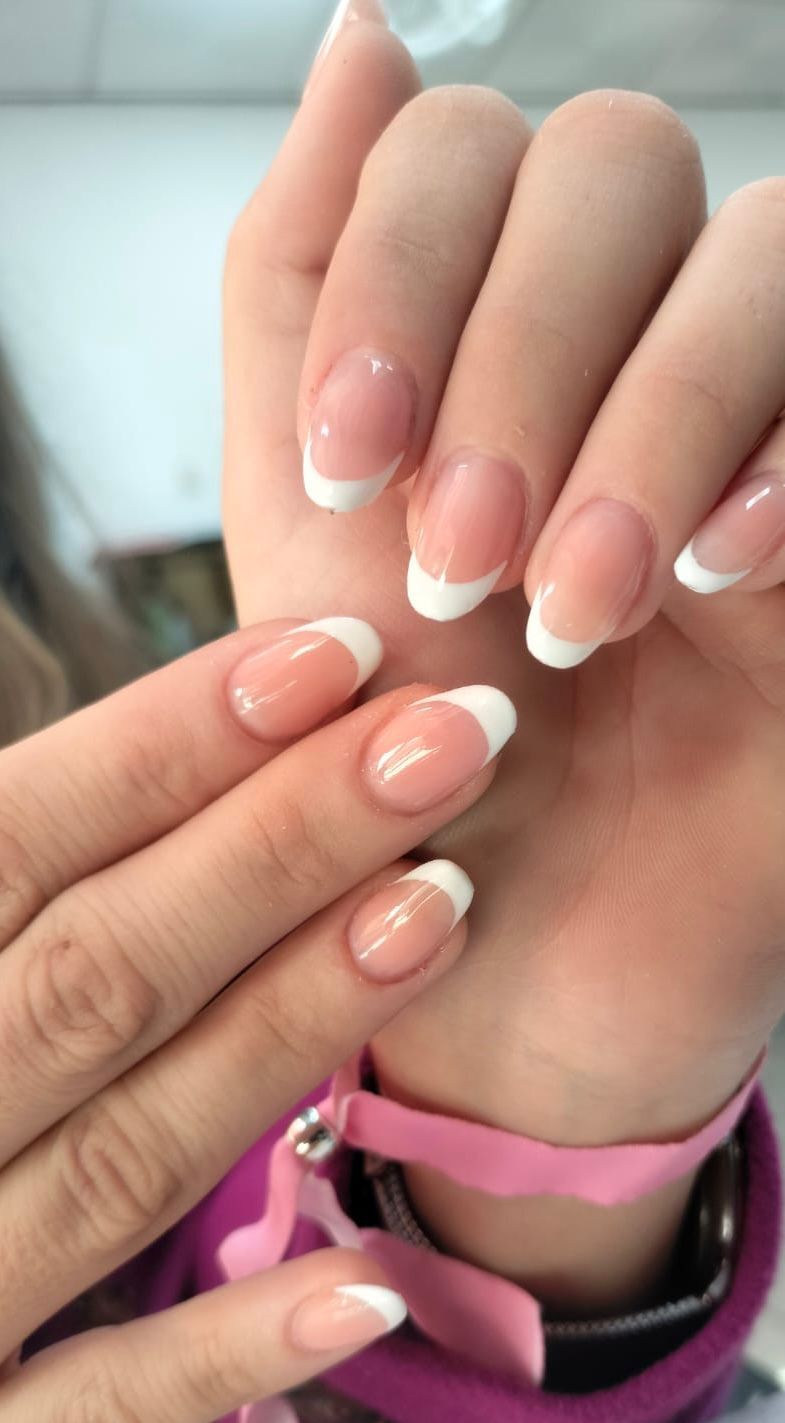 Un primer plano de las uñas de una mujer con manicura francesa.