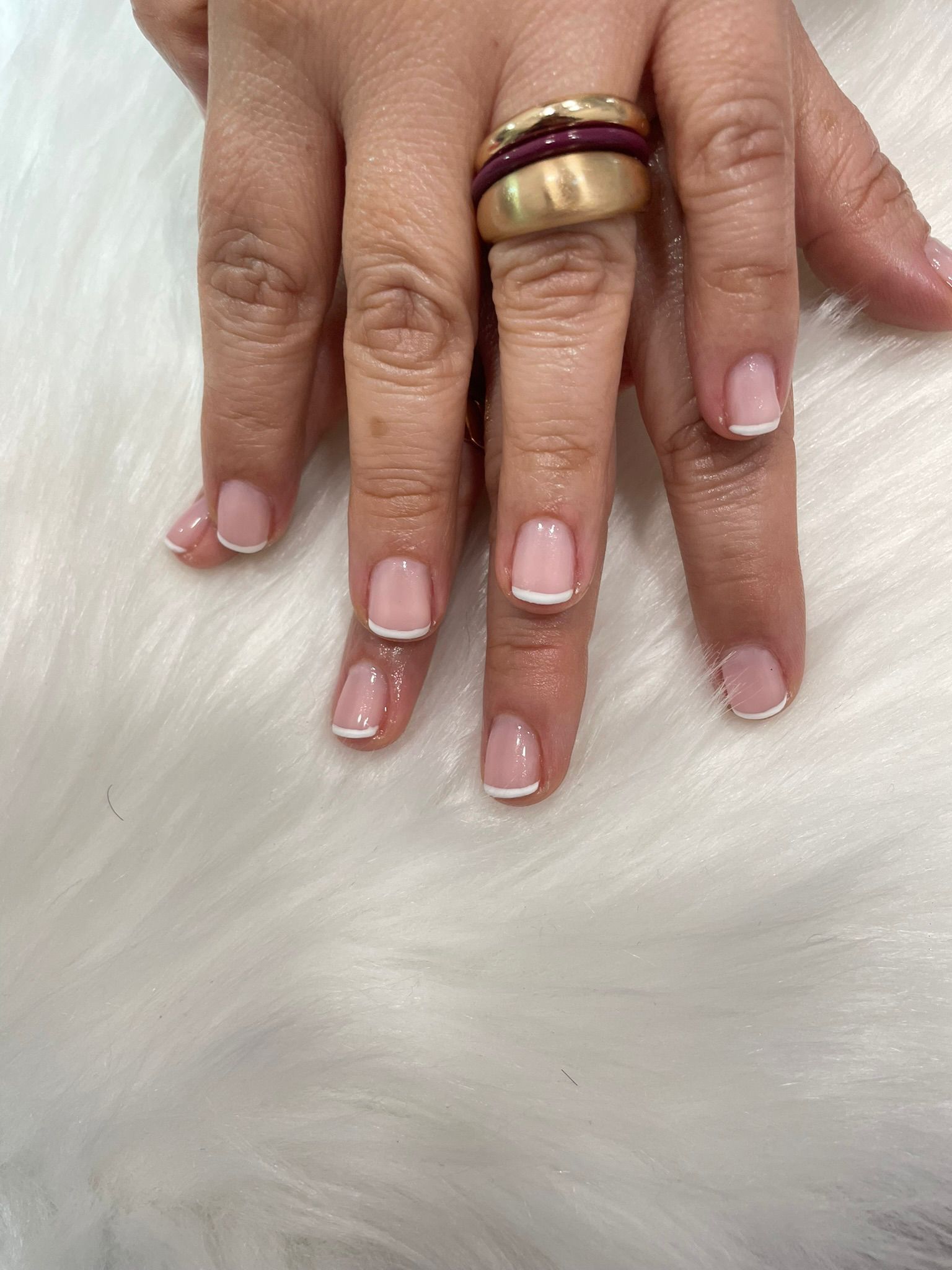 La mano de una mujer con uñas rosas y anillos en los dedos.