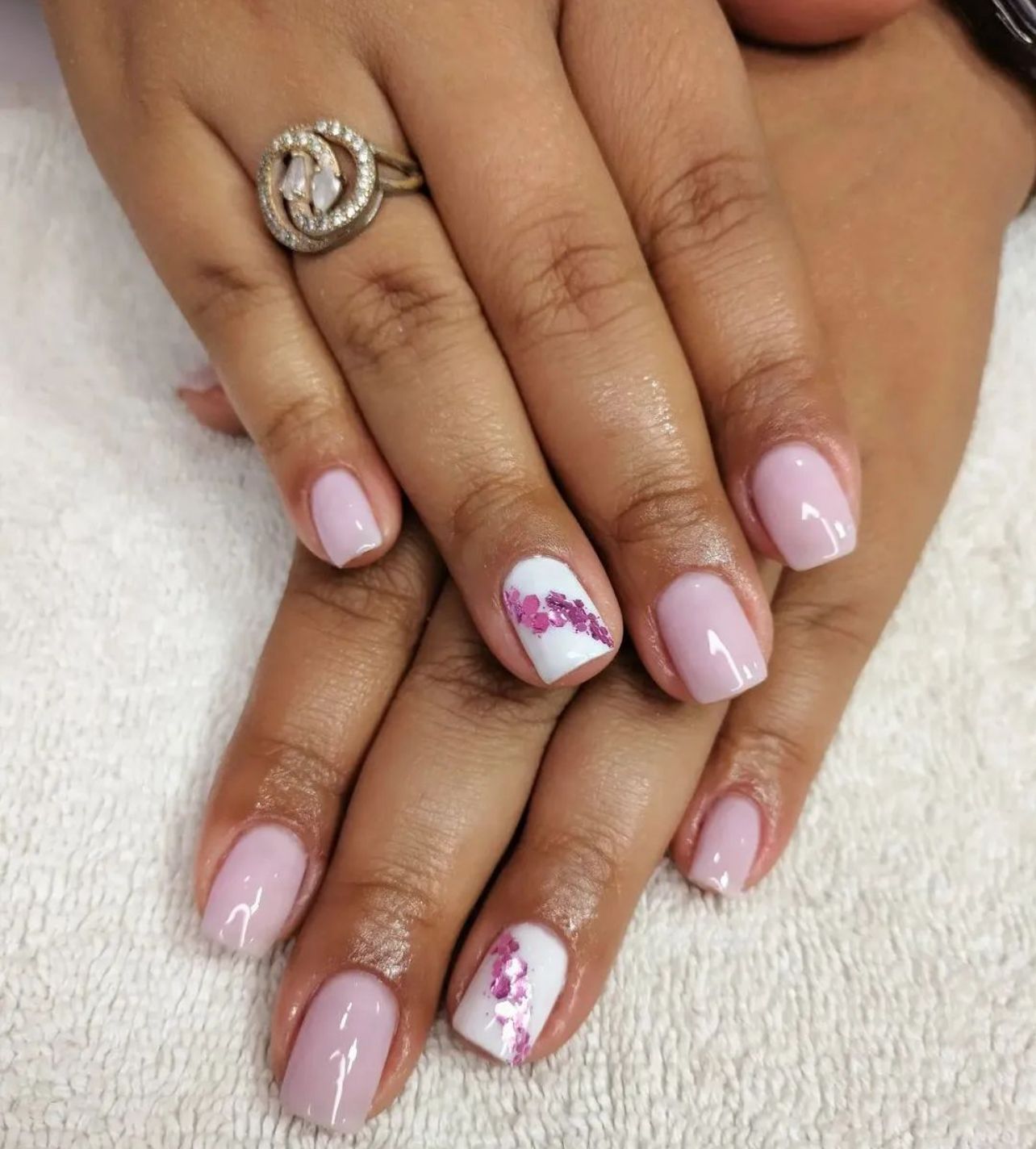 La mano de una mujer con uñas rosas y un anillo en el dedo.