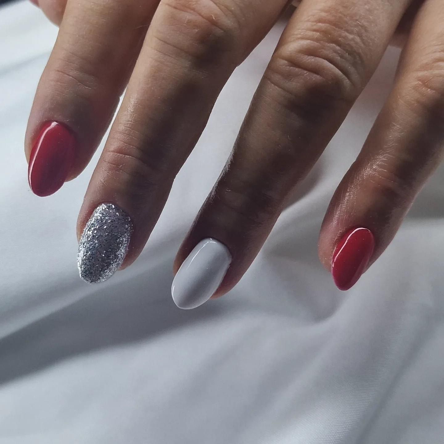 Un primer plano de las uñas de una mujer con esmalte rojo y blanco.