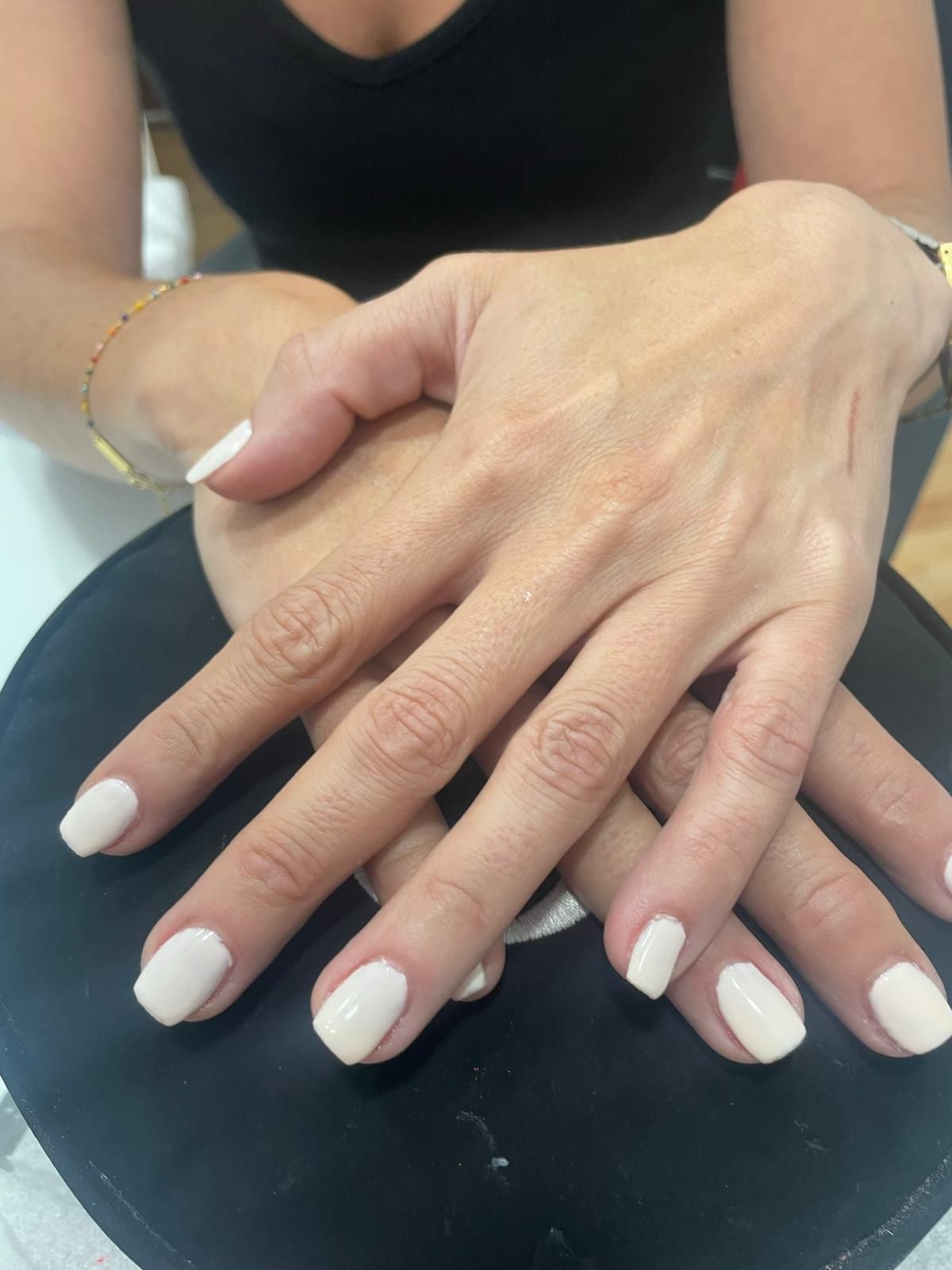 Un primer plano de las manos de una mujer con uñas blancas.