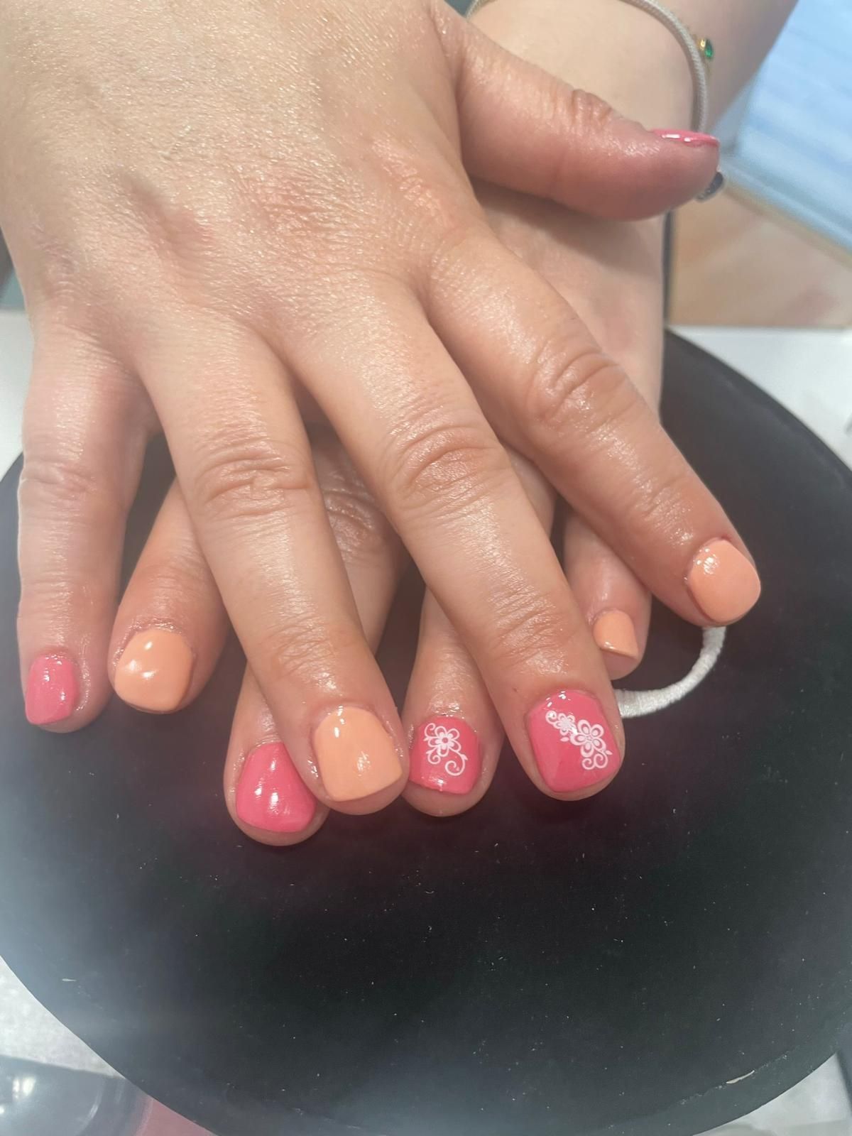 Un primer plano de las manos de una mujer con uñas rosas y naranjas.