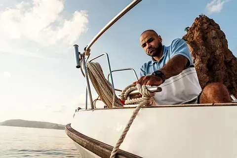 Un hombre está conduciendo un velero en el océano.