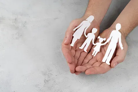 Una persona sostiene en sus manos un recorte de papel de una familia.