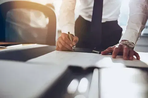 Un hombre con traje y corbata está firmando un documento.