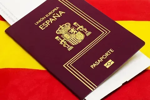 Un pasaporte español está encima de una bandera amarilla y roja