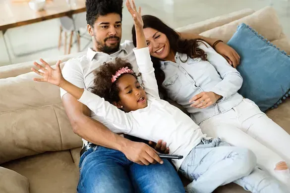 Una familia está sentada en un sofá viendo la televisión.