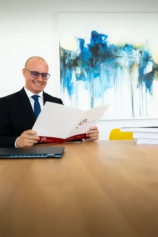 Un hombre con traje y corbata está sentado en una mesa sosteniendo un trozo de papel.