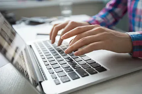 Una persona está escribiendo en una computadora portátil.