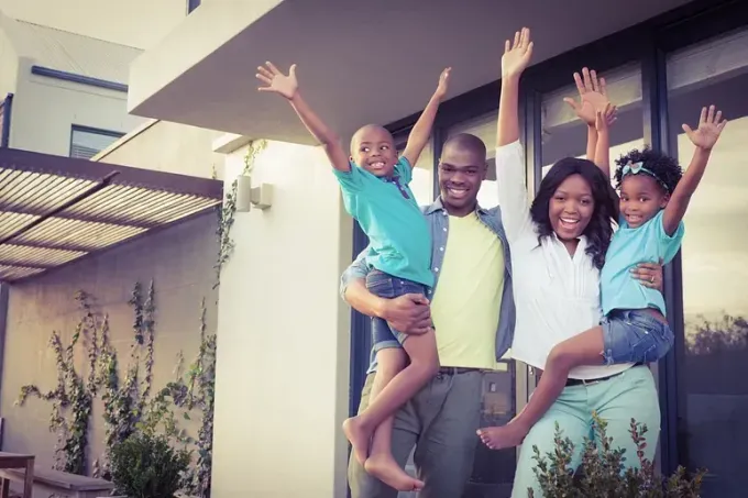 Una familia posa para una fotografía frente a su nueva casa.