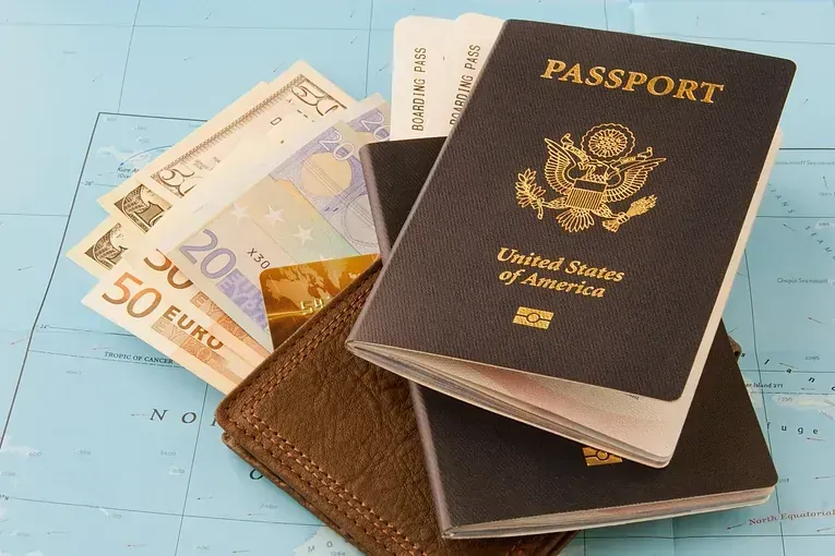 Una pila de pasaportes encima de una billetera llena de dinero.