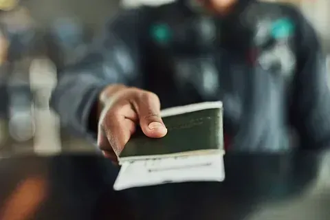 Un hombre le da un pasaporte a otro hombre en un aeropuerto.