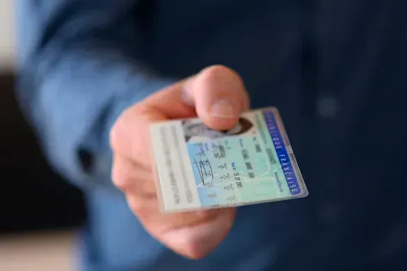 Un hombre sostiene una licencia de conducir en su mano.