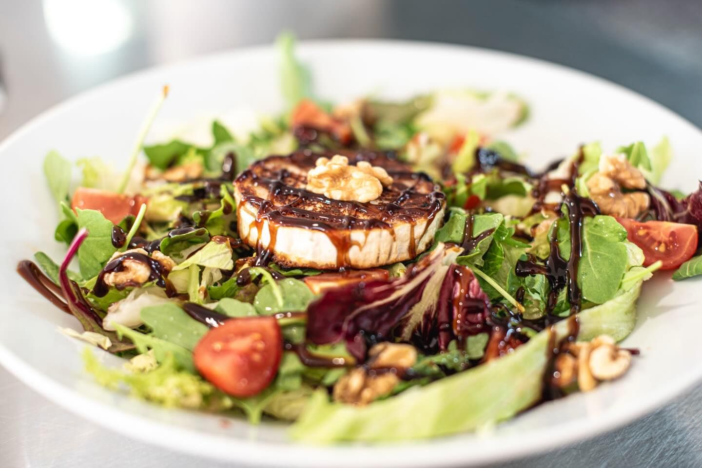 Un primer plano de una ensalada con un trozo de queso encima.