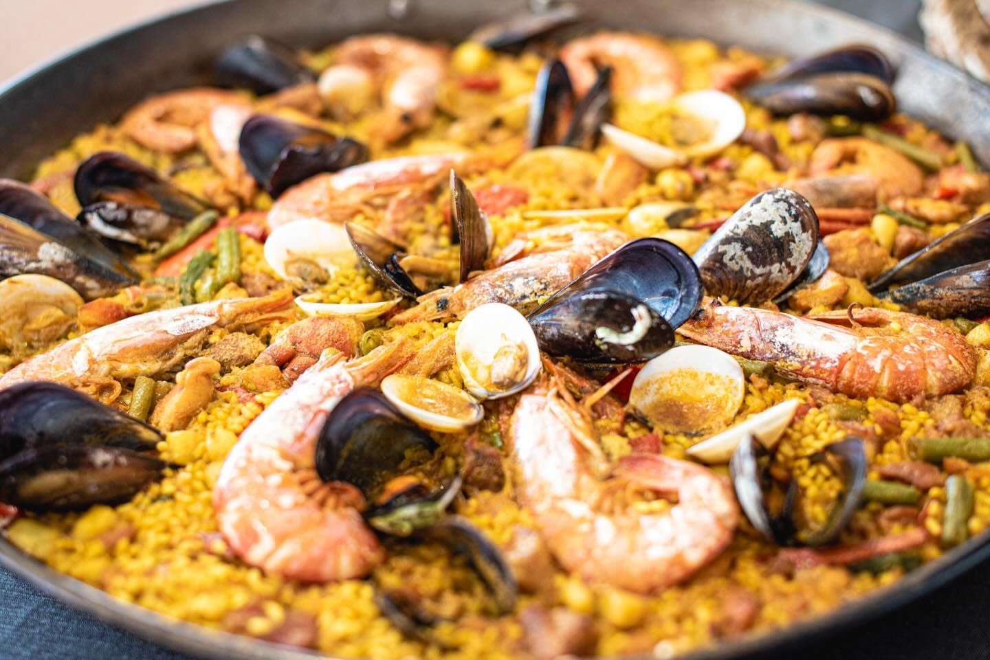 Una sartén llena de arroz, camarones, mejillones y otros mariscos.