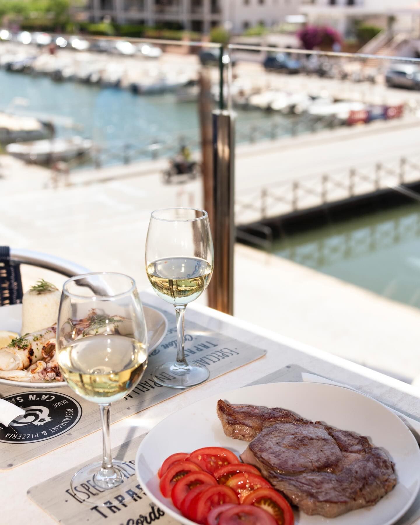 Un plato de comida y una copa de vino en una mesa.