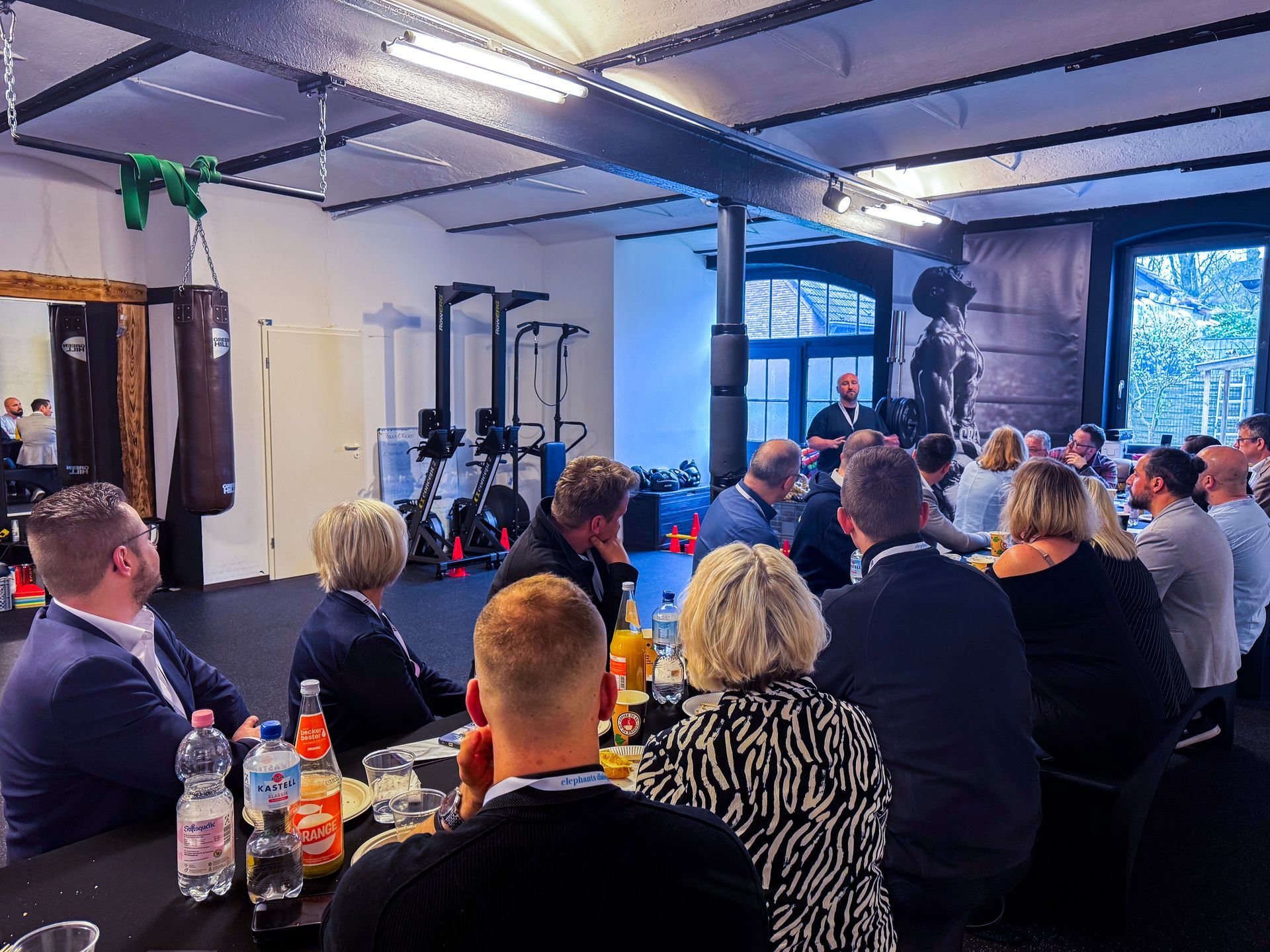 viele Menschen sitzen auf der Bank und hören einem Redner zu