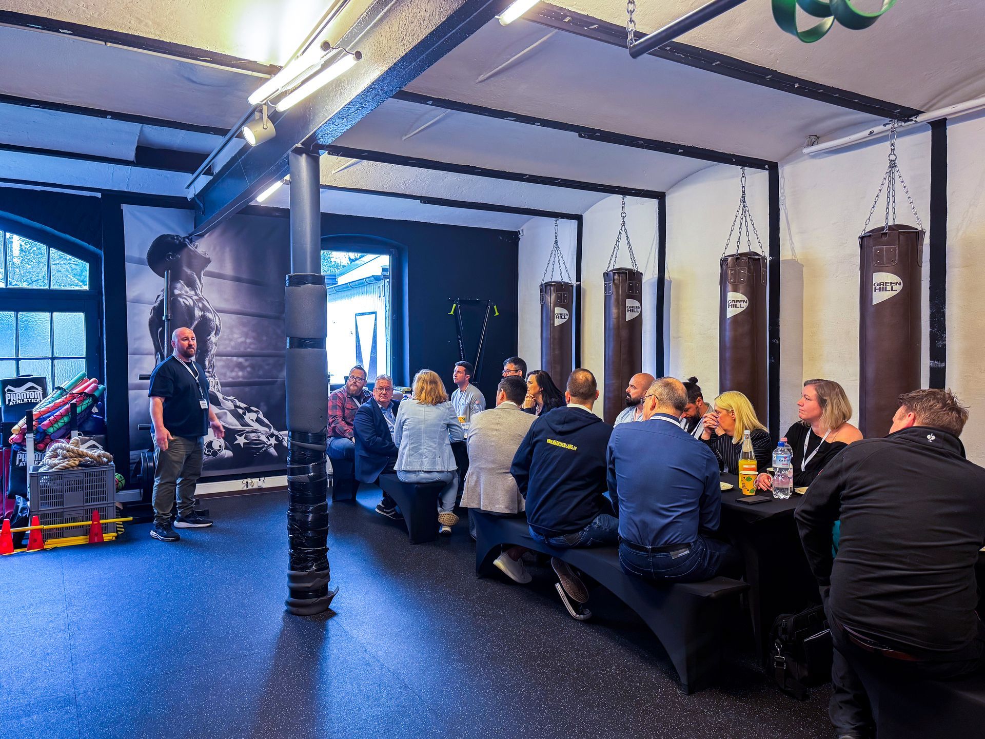 Willi Braun steht im Boxstudio in Mülheim vor einer Gruppe sitzender Teilnehmer beim Unternehmerfrühstück