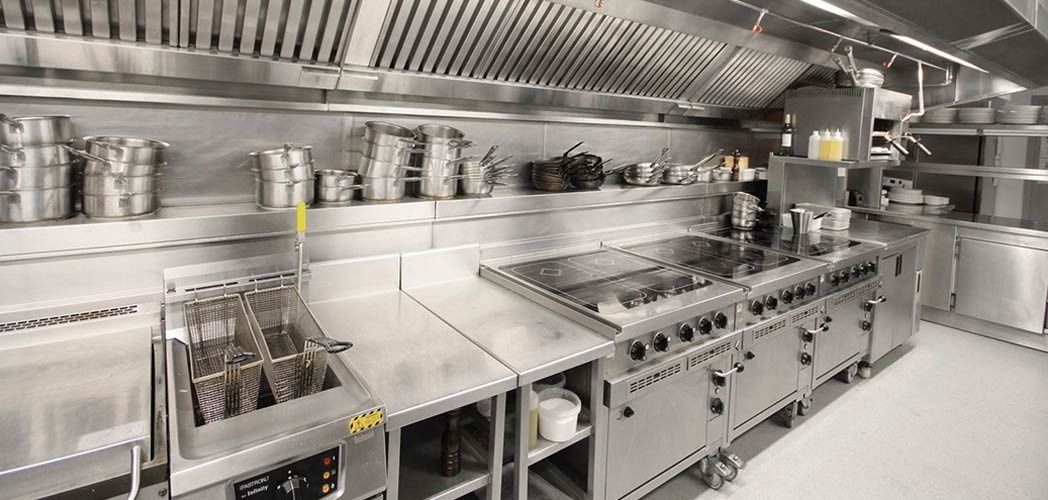 Una cocina con muchos electrodomésticos de acero inoxidable y ollas y sartenes.