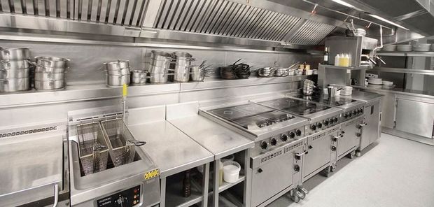 Una cocina con muchos electrodomésticos de acero inoxidable y ollas y sartenes.