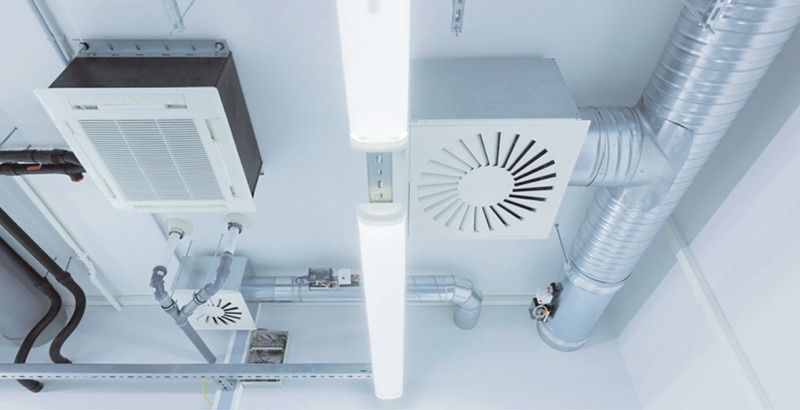 Un techo con muchas tuberías y un ventilador encima.