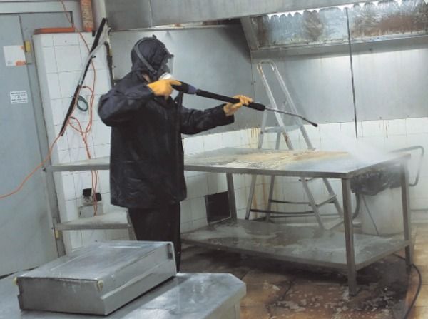 Un hombre está usando una hidrolavadora en una cocina.