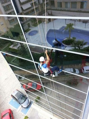 Un hombre está limpiando las ventanas de un edificio alto.