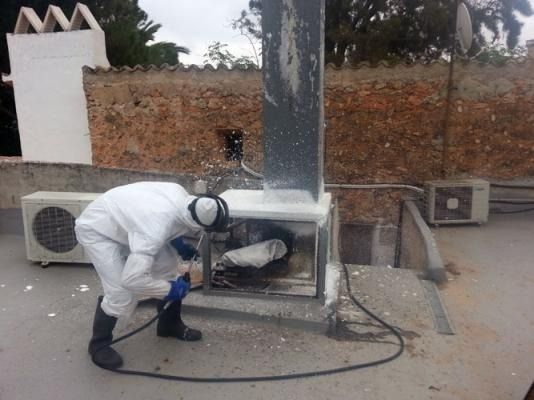 Un hombre con un traje blanco está trabajando en un aire acondicionado.