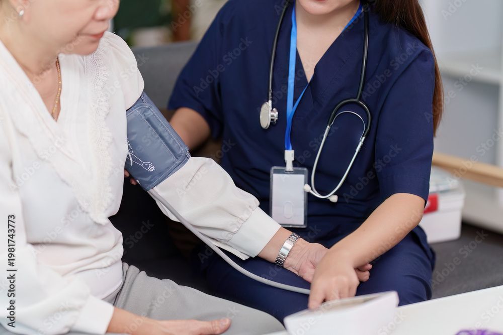 Eine Krankenschwester überprüft in einer Klinik den Blutdruck am Handgelenk eines Patienten.