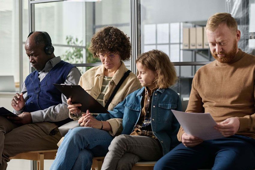 Plusieurs adultes et un enfant assis sur un canapé regardant des documents