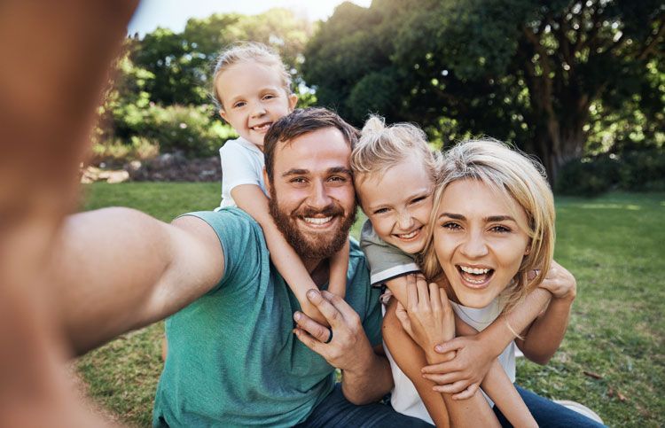 Famille avec deux enfants souriant en extérieur
