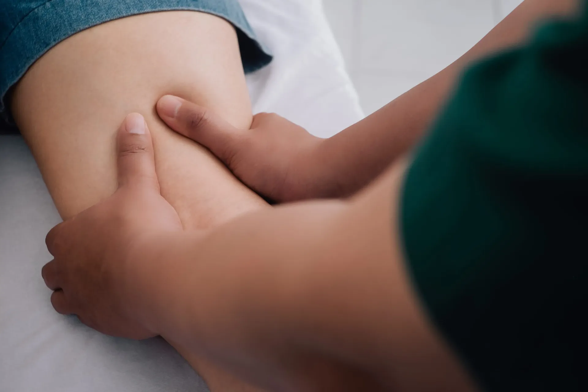 Manos que masajean la parte superior del muslo de una persona.