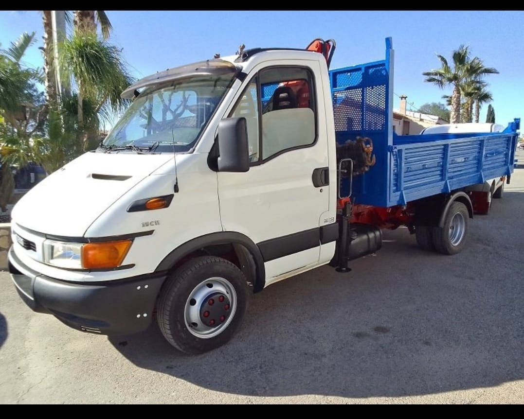 Un camión blanco con una caja azul está estacionado en un estacionamiento.