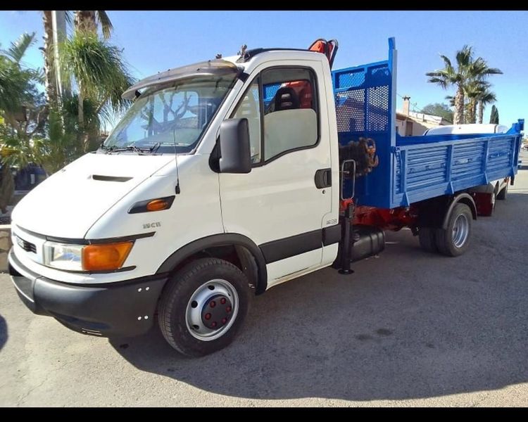 Un camión blanco con una caja azul está estacionado en un estacionamiento.