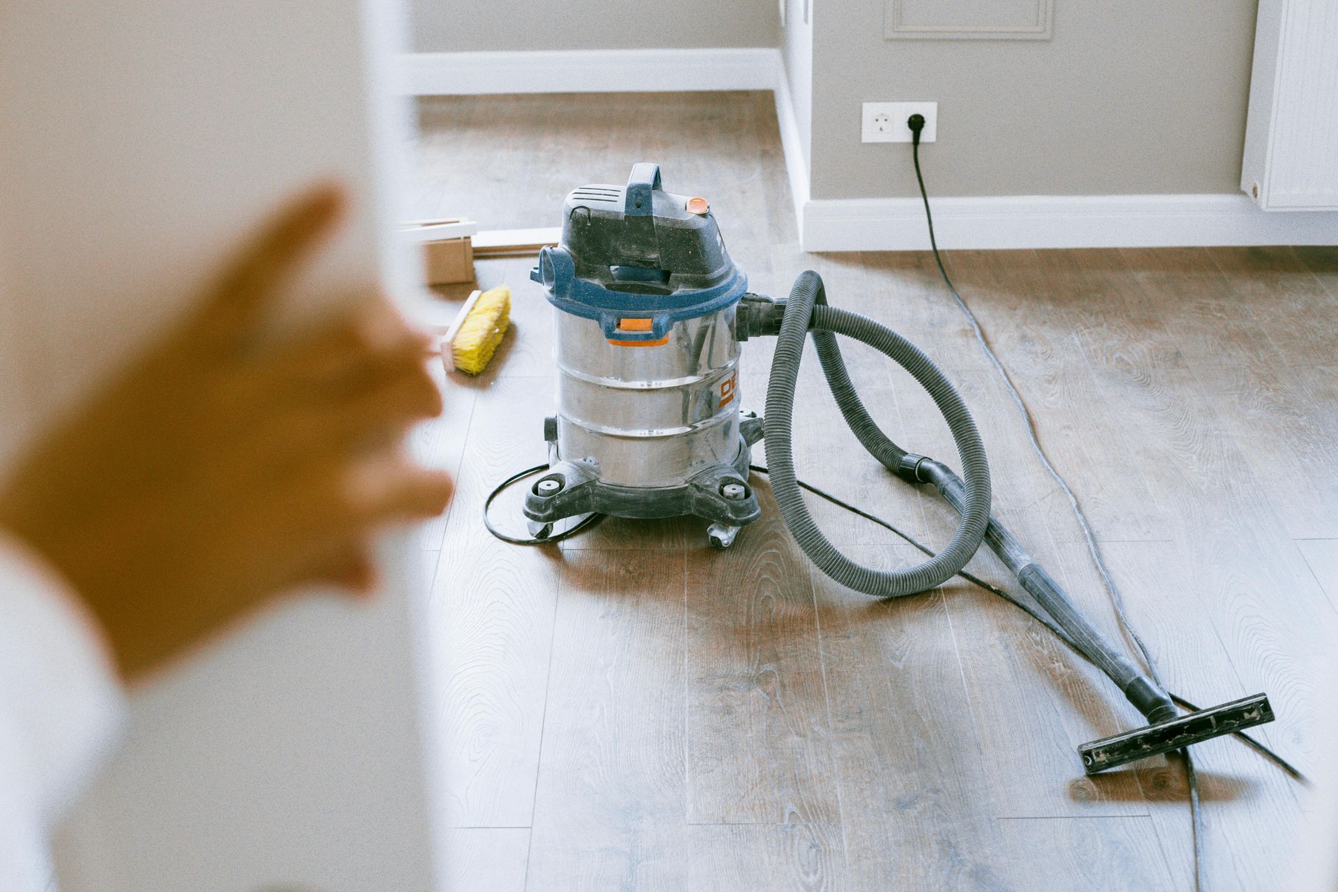 Una aspiradora está colocada sobre un piso de madera en una habitación.