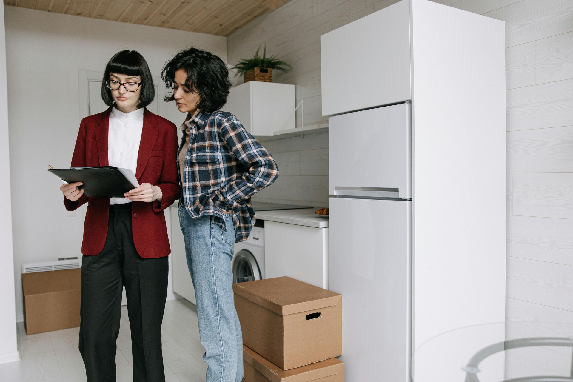 Dos mujeres están paradas una al lado de la otra en una cocina mirando un portapapeles.