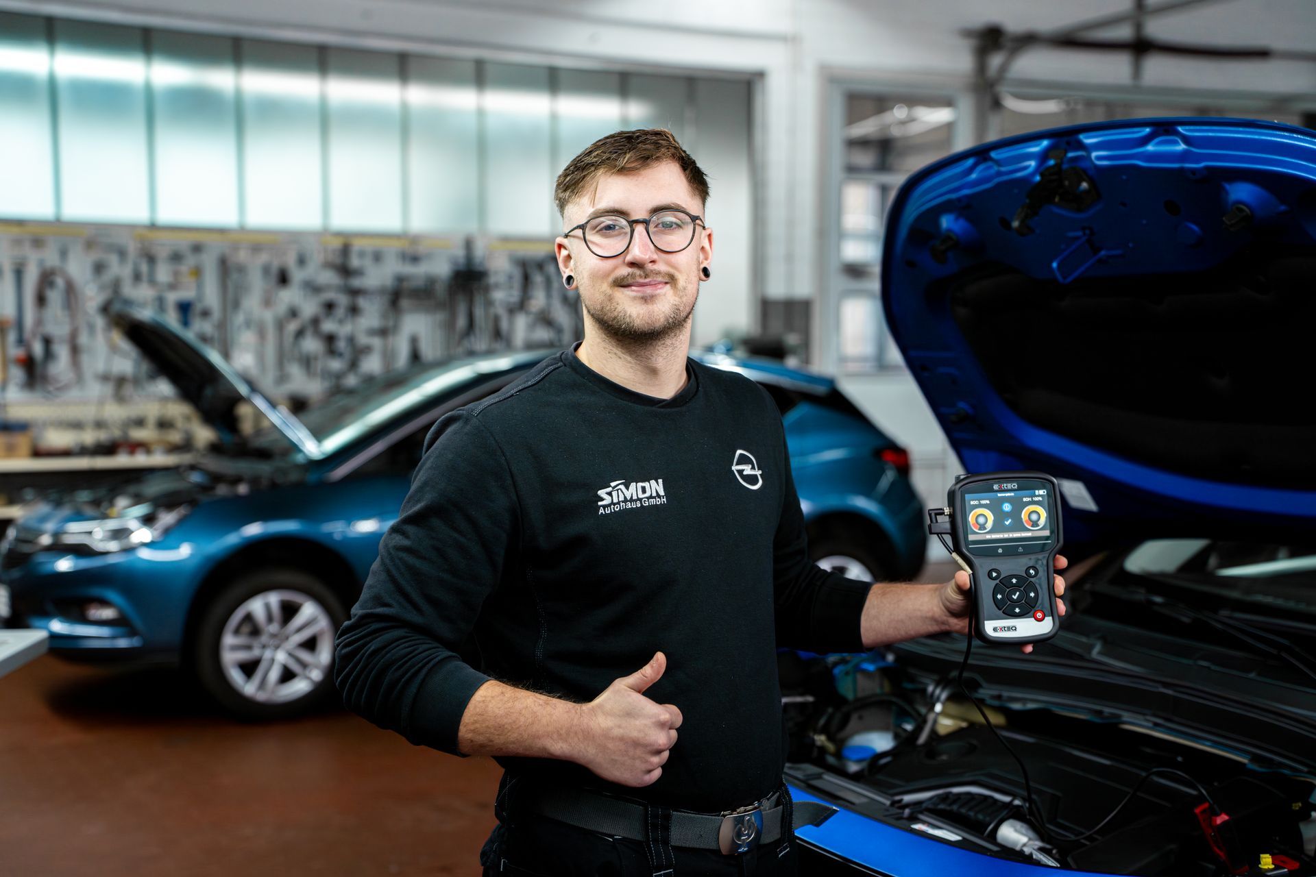 Kfz-Mechatroniker führt mit einem Diagnosegerät eine Fahrzeuganalyse in der Werkstatt durch.