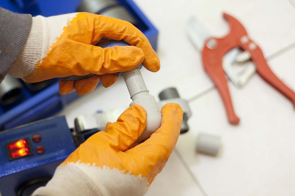 Una persona que lleva guantes naranjas está trabajando en una tubería.