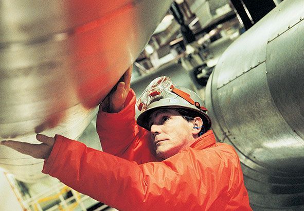 Un hombre con una chaqueta naranja y un casco está trabajando en una tubería.