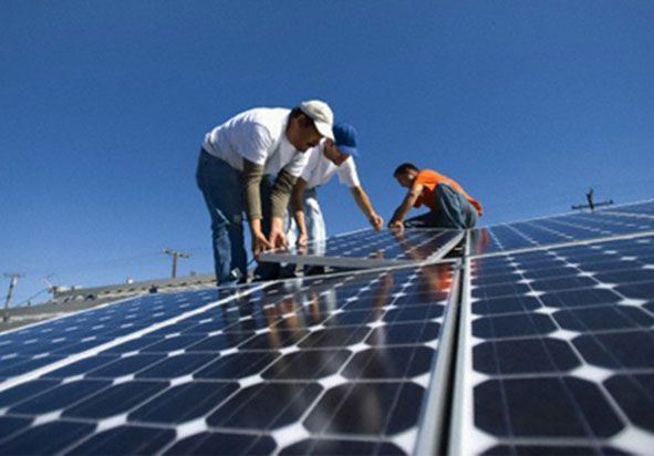 Tres hombres están trabajando en paneles solares en un tejado.