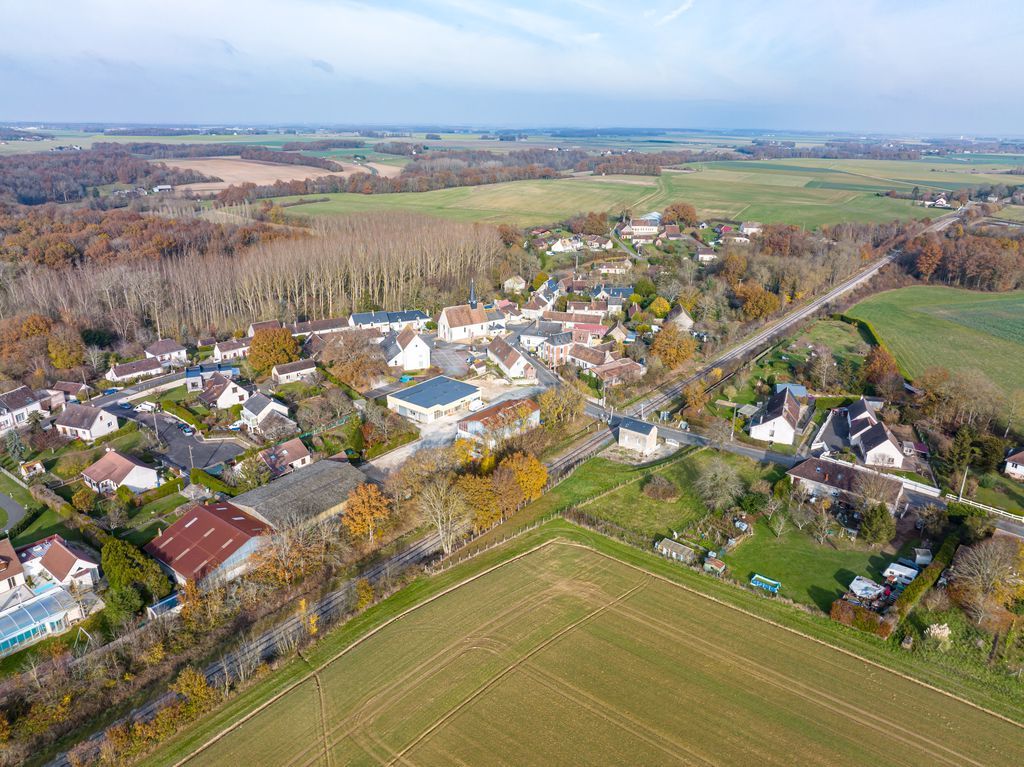 Vue aérienne d'un village rural avec des maisons, des routes, des champs et des arbres d'automne sous un ciel nuageux
