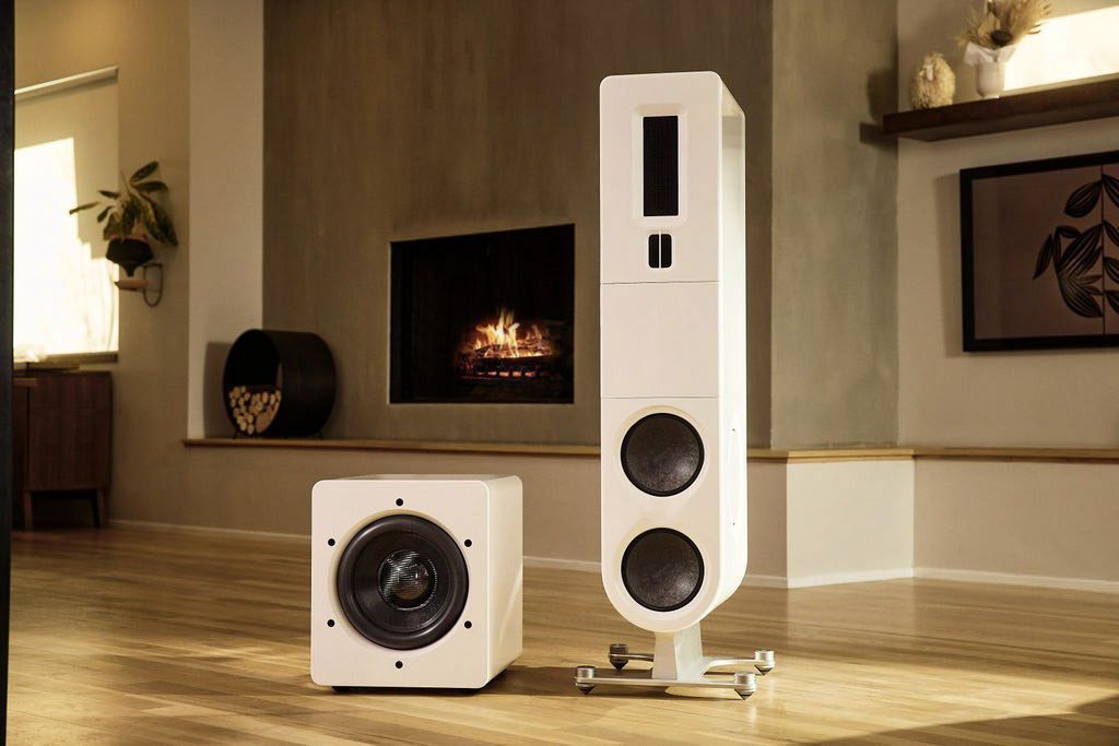 Modernes Wohnzimmer mit einem weißen Standlautsprecher und einem weißen Subwoofer auf dem Boden.