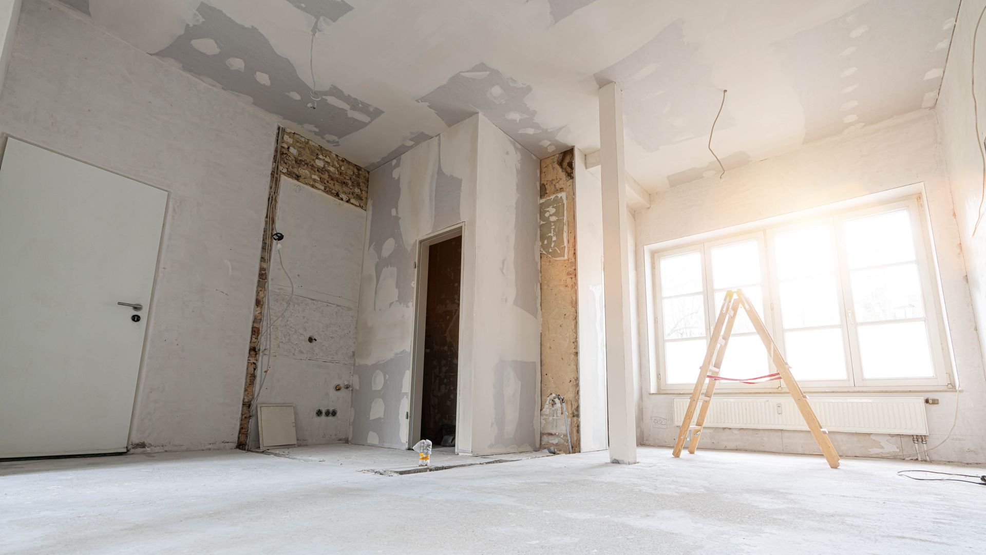 Il y a une échelle au milieu d'une pièce en rénovation.