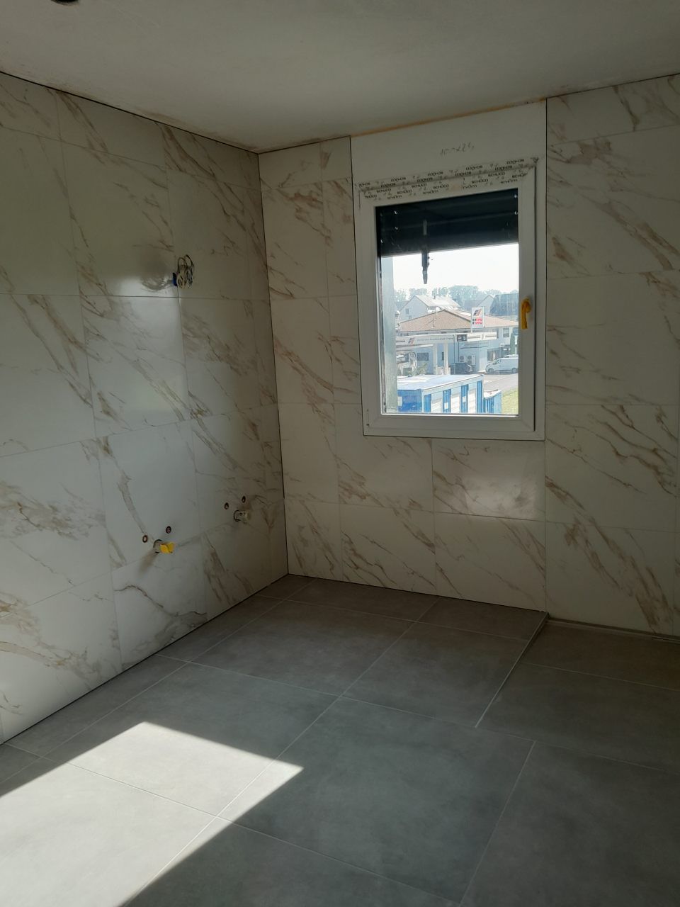 Une pièce vide avec des murs en marbre et une fenêtre.