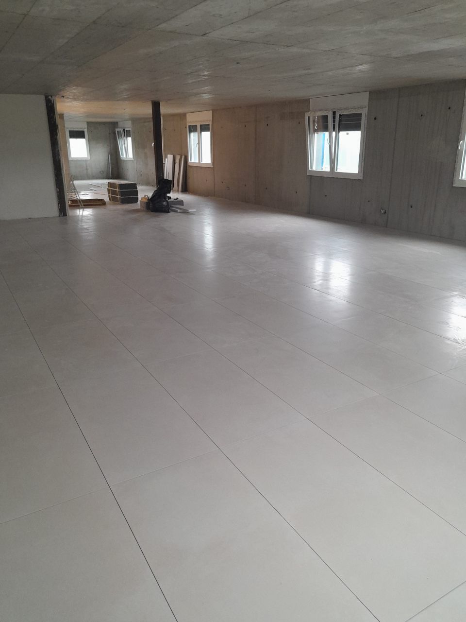 Une grande pièce vide avec un sol carrelé blanc et beaucoup de fenêtres.