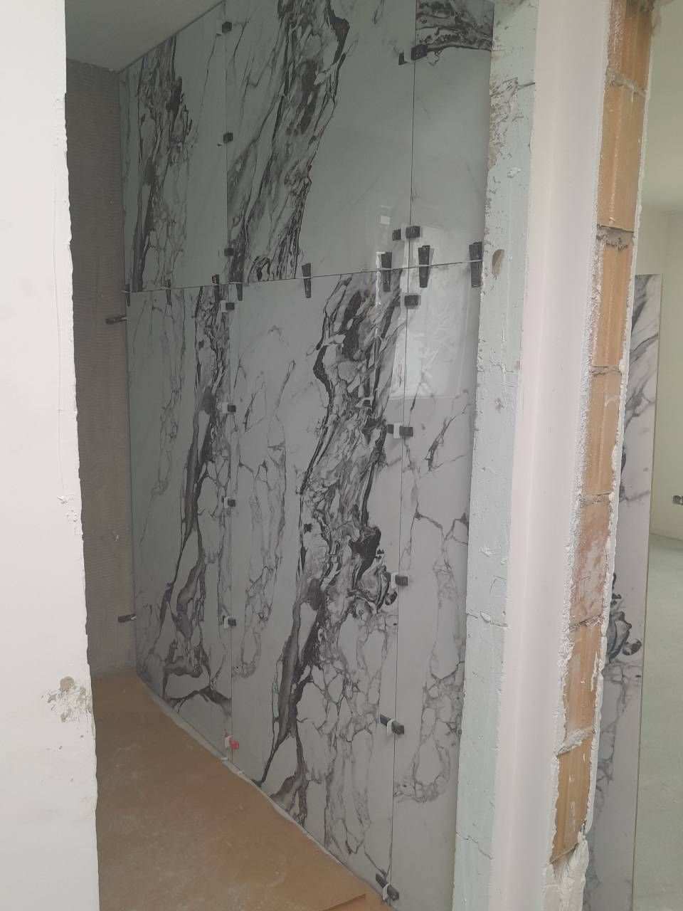 Un couloir avec un mur en marbre et une porte.