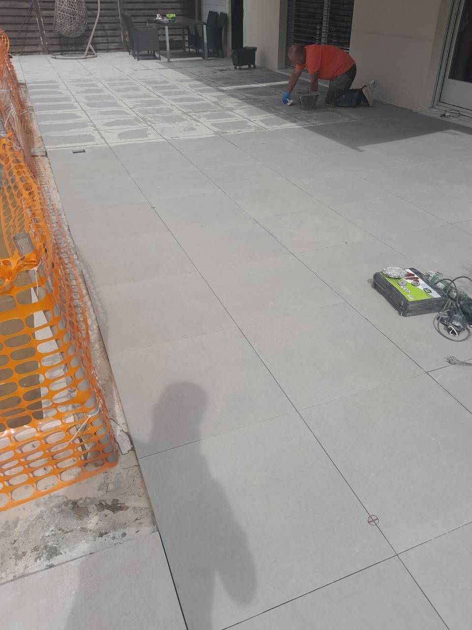 Un homme pose des carreaux sur un patio.