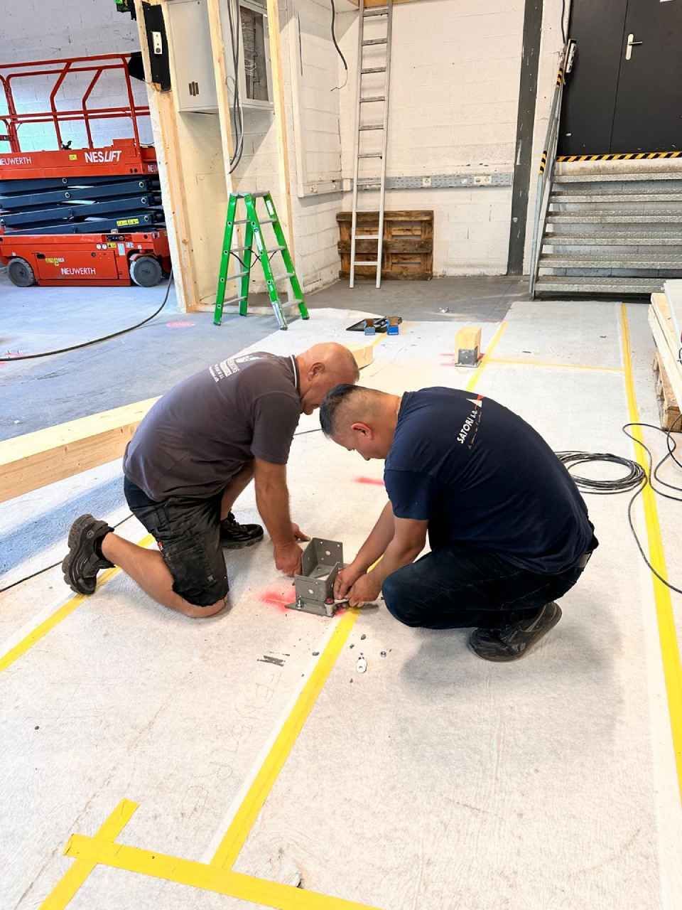 Deux hommes travaillent sur le sol d'un immeuble.