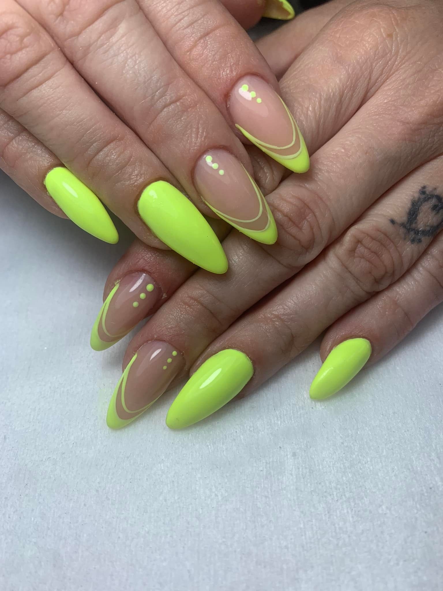 Manos con uñas en forma de almendra de color amarillo neón; algunas con base transparente y contorno amarillo.