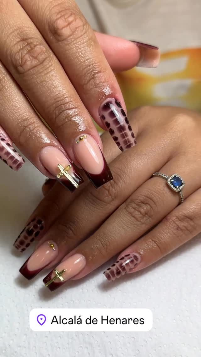 Manos de una persona con uñas largas en forma de ataúd con puntas francesas, estampado animal y detalles dorados.